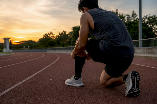 Runner adjusting compression calf sleeve on outdoor track