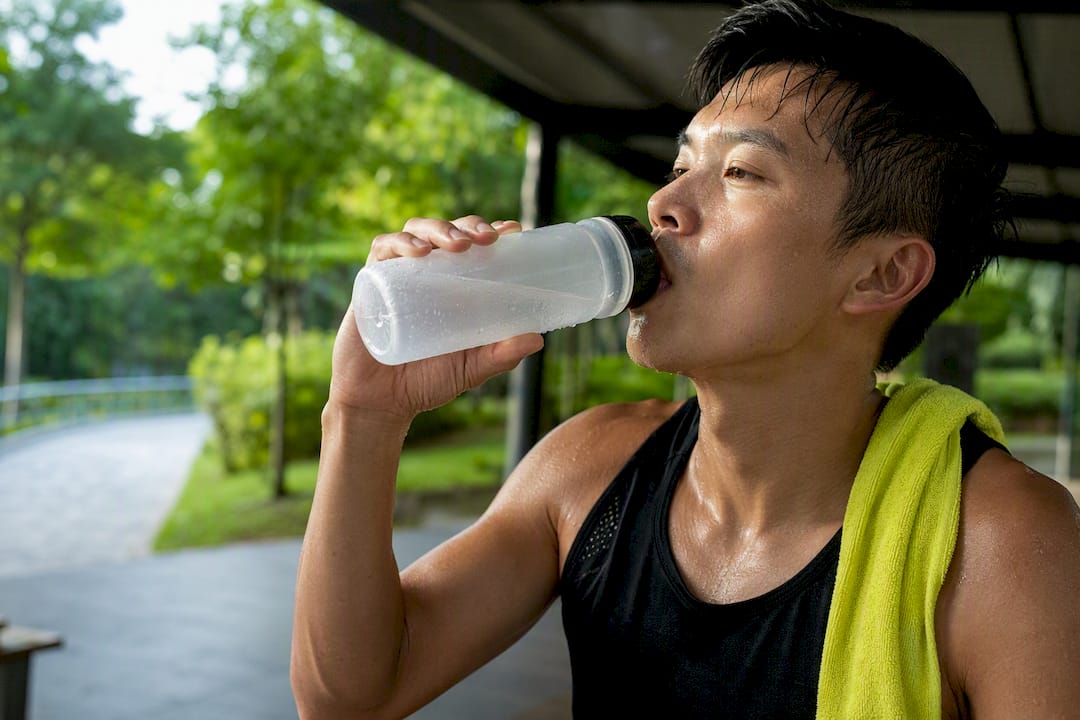 Runner sipping hydration during humid Singapore training